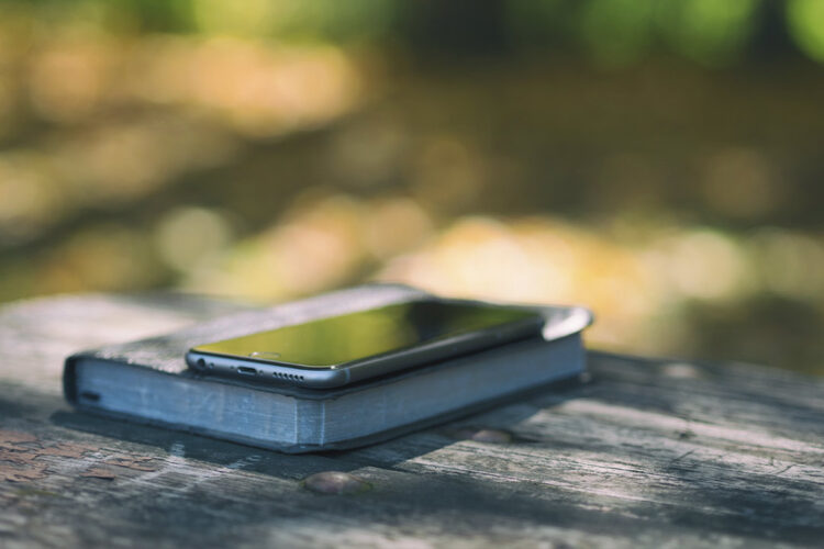 Smartphone apoyado sobre una Biblia, representando la interacción entre tecnología y espiritualidad